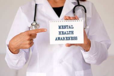 Akıl sağlığı farkındalığı konsepti. Doktor defterindeki kelimeleri işaret ediyor.