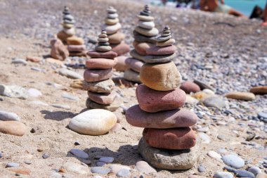 Plajda özenle dengelenmiş pürüzsüz taşlar yığını deniz kıyısındaki dönüm noktalarını ve sükuneti simgeliyor..