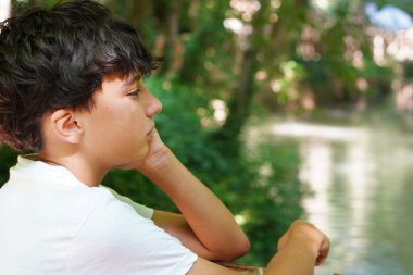 üzgün ve düşünceli genç çocuk doğayı gözlemliyor.