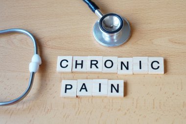 Tıbbi kavramlar. kronik ağrı. kelime ahşap harflerle steteskopla yazılmış..