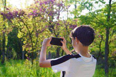 Cep telefonuyla fotoğraf çeken genç bir çocuğun portresi.