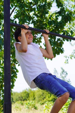 Ergenler ve sağlıklı alışkanlıklar. Sıska çocuk barfiks çekiyor..
