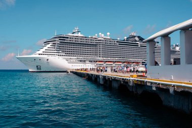 Meksika 'daki Cozumel rıhtımında demirlemiş bir yolcu gemisi. Yolcuları rıhtıma indiriyor. Canlı sahne, Karayip maceralarına başlayan gezginlerin heyecanını yakalıyor..