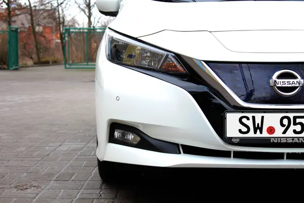 Vinnytsia, Ukrayna; 21 Şubat 2024. Beyaz Nissan Leaf farları. Elektrikli araba Nissan Leaf radyatör ızgarası. Arabanın önüne Nissan Leaf. Nissan Yaprak logosu ve amblemi. 