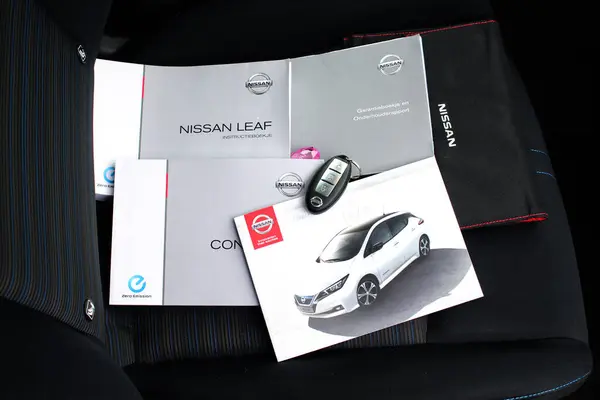 Vinnytsia, Ukrayna; 21 Şubat 2024. Elektrikli araba Nissan Leaf araba anahtarları. Nissan Leaf hizmet defteri. Araba servisi. Tarih hizmet kitabı.