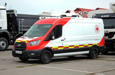 Vinnytsia, Ukrayna; 23 Mart 2024. Ford Transit tıbbi minibüsü şehir caddesinde. Ambulans arabası. Kırmızı ve beyaz Ford Transit Mobil Klinik Minibüsü. Özel Mobil Tıbbi Minibüs. Kızıl Haç arabası. Kızıl Haç aracı.