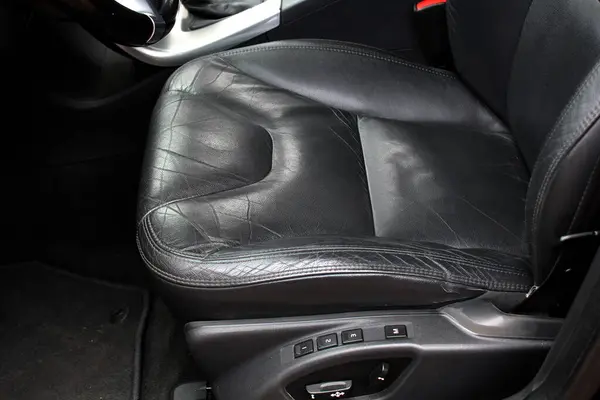 Black leather drivers seat bottom. Leather drivers seat with signs of wear. Front driver seat with leather texture. Interior detail.