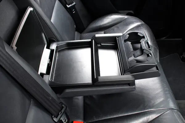 Modern SUV 'de masa ve bardak tutacağı olan bileklik. Arka koltuklarda koltuk var. Aracın arka koltuğunda bardak tutacağı olan siyah deri bir kol sehpası..