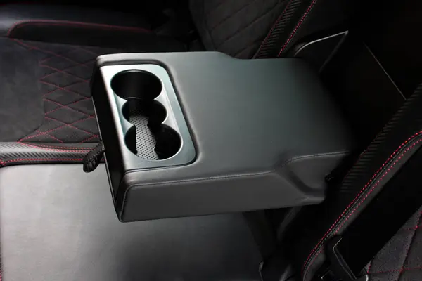 İçinde bardak tutacağı olan bileklik. Deri rahat siyah yolcu koltukları ve kolluk. Lüks modern arabanın içi siyah deri. Modern araba iç dekorasyonu. Arka yolcu koltukları.