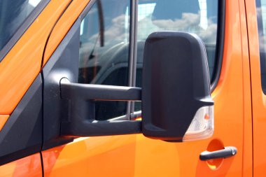 Turuncu kargo minibüsünün siyah dikiz aynası. Modern kargo minibüsünde siyah bir dikiz aynası var. Kargo aracının dikiz aynasını kapat. Güvenli sürüş sistemi.