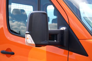 Turuncu kargo minibüsünün siyah dikiz aynası. Modern kargo minibüsünde siyah bir dikiz aynası var. Kargo aracının dikiz aynasını kapat. Güvenli sürüş sistemi.
