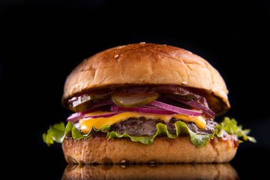 Sığır etli burger, peynir, siyah tabakta sebze. Karanlık Arkaplan. Kapat.