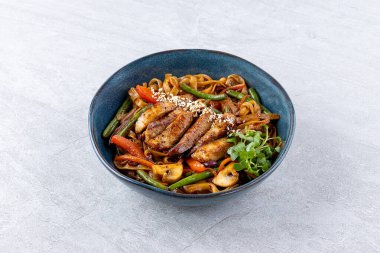 Kızarmış Udon, biftek ve sebzeli, koyu taş masada.,