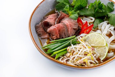 Pho Bo traditional Soup with beef, rice noodles, ginger, lime, chili pepper in bowl. Close up. Vietnamese and Asian cuisine