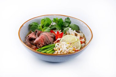 Pho Bo traditional Soup with beef, rice noodles, ginger, lime, chili pepper in bowl. Close up. Vietnamese and Asian cuisine