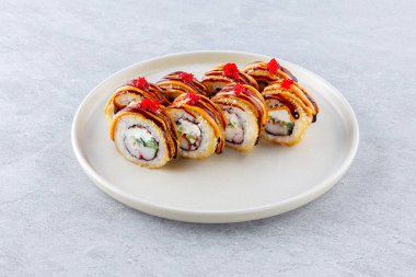 Surimi, salatalık ve krem peynirli sıcak suşi, baharatlı ve unagi soslu, masago havyarıyla süslenmiş.,