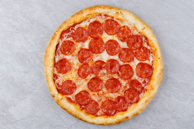 Sosisli biberli pizza ve gri beton tezgahta peynirli mozzarella. Üst görünüm