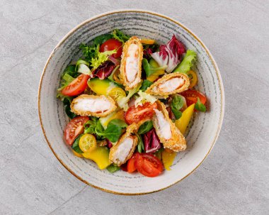 Panko karidesli salata, avokado ve mango. Restoran menüsü için gri bir arka plan.