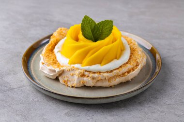 Taze mango ve tutku meyveli kremalı pasta Pavlova kaykay, taş ya da beton arka planda krema.