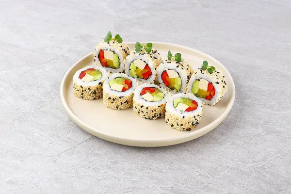 İçi tofu, avokado, kırmızı dolma biber ve turşulu taze mikro yeşilliklerle süslenmiş taze, taze, renkli bir ısırık için içi tofu ve siyah sushi tohumlarıyla kaplı bir vejetaryen suşi rulosu..