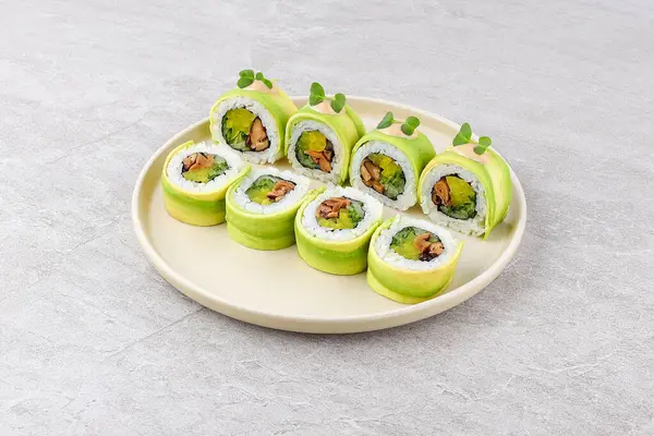 İnce avokado dilimlerine sarılı suşi rulosu, marinaya batırılmış mantarlar, kıtır turp ve baharatlı mayonez ve mikroyeşilliklerle kaplı baharatlı pirinç, nötr bir seramik tabakta servis edilir..