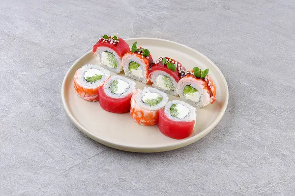 Yumuşak karides, çıtır pirinç incileri ve mikro yeşilliklerle kaplı krem peynirli ve avokadoyla dolu bir suşi rulosu, tarafsız bir arkaplanda minimalist bir tabakta servis ediliyor..
