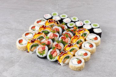 Canlı bir suşi seti klasik Kaliforniya rulolarını karides, somon, avokado, krem peynir ve mango soslu ekmeklerle birleştiriyor. Hepsi susam tohumları ve tobiko ile kaplanmış. Renkli, lezzetli bir aperatif olarak paylaşmak için mükemmel..