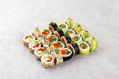 Çeşitli çeşit vejetaryen suşi dürümleri avokado tofu kırmızı çan biberi salatası ve pirinç sosuna sarılmış salatalık ve kremalı susam tohumu ve mikro yeşillikler...