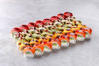 Üzerine taze somon, ton balığı ve mango dilimleri, yılan balığı sosu ve susam tohumlarıyla süslenmiş ejderha stili suşi ruloları..