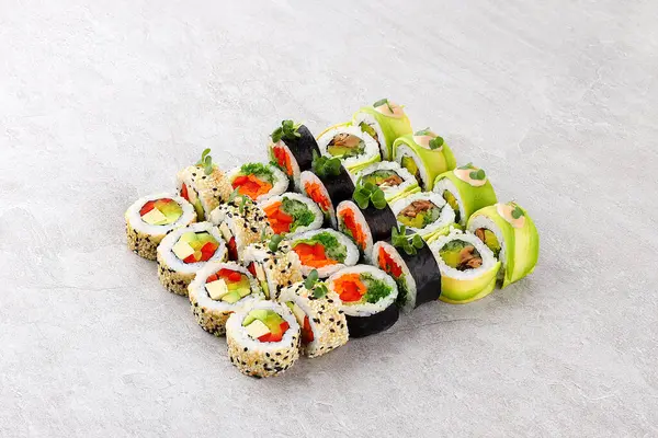 Çeşitli çeşit vejetaryen suşi dürümleri avokado tofu kırmızı çan biberi salatası ve pirinç sosuna sarılmış salatalık ve kremalı susam tohumu ve mikro yeşillikler...