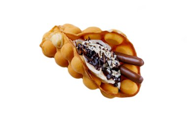 Altın yumurtalı waffle bir koniye katlandı ve içinde muz dilimleri, krema, siyah çikolata çubukları, badem taneleri ve zengin çikolata parçacıkları vardı..