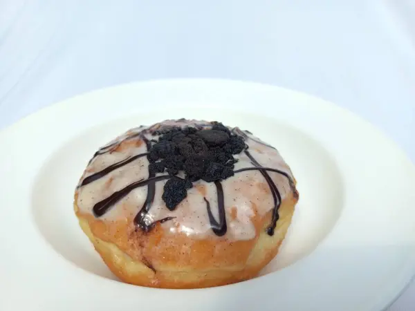 Beyaz arka planda izole edilmiş lezzetli donut. Çikolatalı bisküvi kırıntıları ve karamel kaplama ile tatlı ikram. Kapatın. Uzayı kopyala Seçici odak.