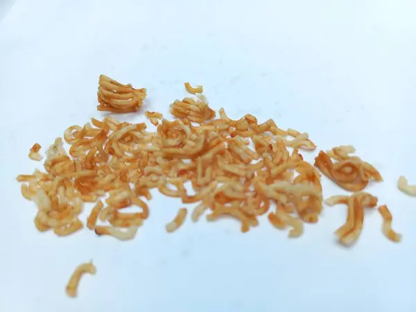 Beyaz arka planda izole edilmiş erişte kırıntıları. Yemek fotoğrafçılığı konsepti. Atıştırmalık fotoğraf fikri, abur cubur reklamı ve yemek blogu yazısı. Yakın plan. Uzayı kopyala Seçici odak.