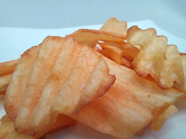 Beyaz arka planda Cassava cipslerinin makro fotoğrafçılığı. Yemek fotoğrafçılığı konsepti. Atıştırmalık markalar ve reklamlar, ayrıca yemek blogu için fotoğraf gönderme fikirleri. Yakın plan. Uzayı kopyala Seçici odak.