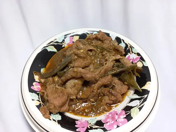 Beyaz arka planda izole edilmiş, çiçek desenli bir kasede kızartılmış biftek. Yemek fotoğrafçılığı konsepti. Kapatın. Uzayı kopyala Seçici odak.