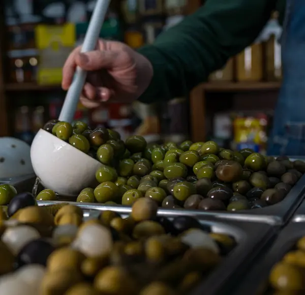 Markette zeytin seçen bir kişinin dikey yakın çekimi