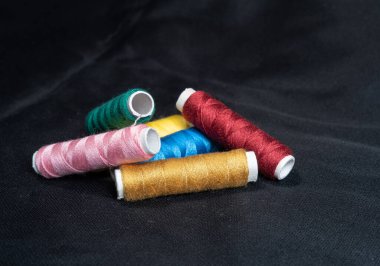 Fotokopi alanı olan koyu bir arkaplanda renkli iplik ve iğne makaraları