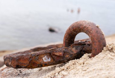 Eski paslı metal zincir sabah denizin kıyısında yatar.