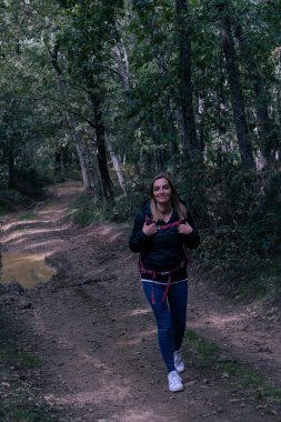 Sonbaharda ormanda yürüyen bir kadının dikey görüntüsü.