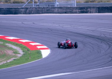 Kırmızı formüllü araba sol köşede sürüyor. Tarihi yarış arabası