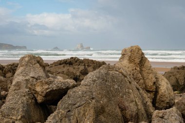 Kayalar ve okyanus manzarası İspanya 'nın kuzeyinden bahar bulutlu bir sabahta arka planda bazı kaya oluşumları ile