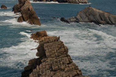 Atlantik Okyanusu 'ndaki kaya duvarının kenarında yürüyen biri. İspanyol kuzey kıyısı. Sinek.