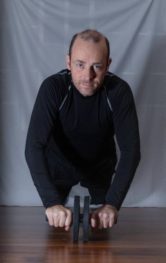 Evde bigudiyle egzersiz yapan orta yaşlı bir adam.