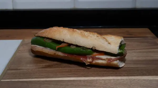 Jambonlu peynirli sandviç ve servis tahtasında yeşil biber.