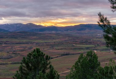 Dağların üzerinde gün batımı ve tepenin üstündeki tarlalar.