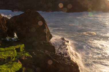 Gün batımında dalgalar kayalara vuruyor.