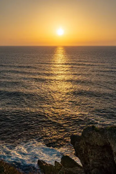 Kayalıklardan denizin üzerinde gün doğumunun güzel bir dikey görüntüsü.