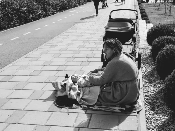 Tiran, Arnavutluk; 14 Şubat 2025: Sokaktaki genç bir kadın bebeğine bakıyor