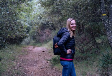 Sırt çantalı genç bir kız ormanda yürüyüş yapıyor.