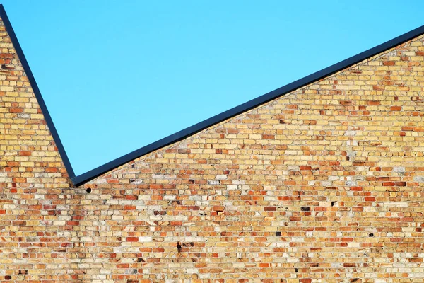 Açık mavi gökyüzüne karşı tuğla bir duvar. 